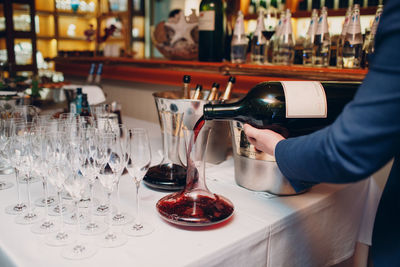 Midsection of man pouring wine in glass at bar