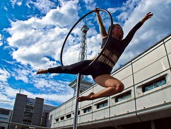 Low angle view of woman with arms raised against sky