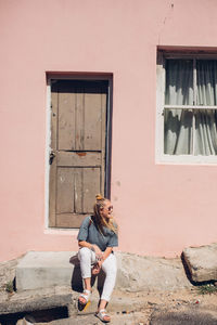 Full length of woman sitting outside house