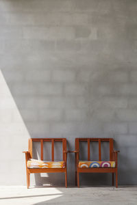 Empty chairs and table against wall