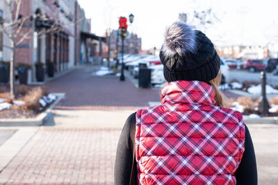 Rear view of woman standing on footpath in city