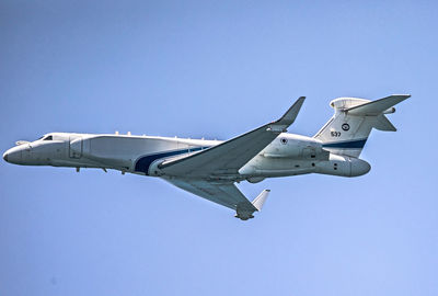 Low angle view of airplane flying against clear blue sky