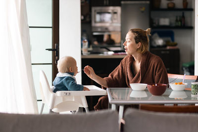 Young woman using mobile phone while sitting at home