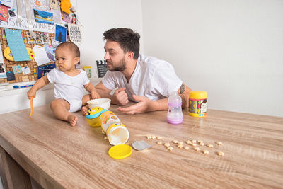 Father and son sitting on table at home