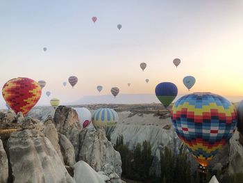 Hot air balloons flying over rock formations at cappadocia during sunset