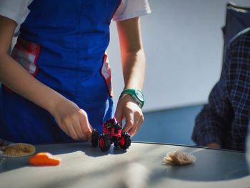 Midsection of girl playing with toy car on table