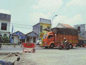 Cars on city street against sky