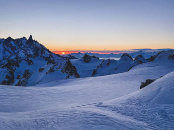 Scenic view of snowcapped mountains against clear sky during sunset