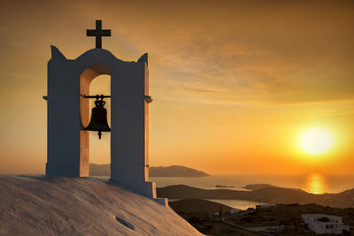 Bell on church against sea during sunset