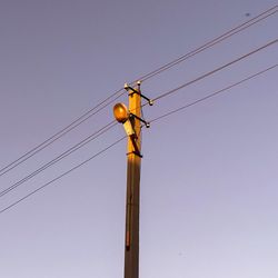 Low angle view of electricity pylon against clear sky