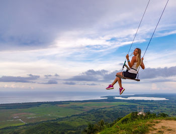 Full length of woman jumping on sea shore against sky