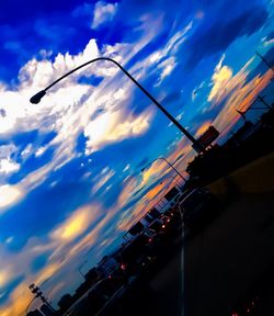 Cars moving on road against cloudy sky