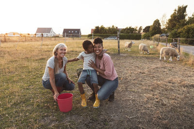 Happy multi-generational family with bucket on field at farm