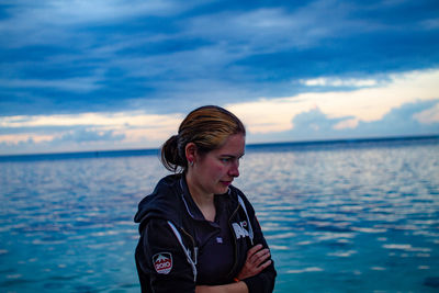 Portrait of young woman looking at sea against sky