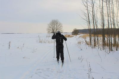 Rear view of man standing on snow covered field