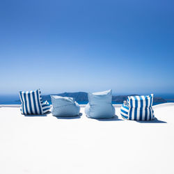 Chairs on beach against clear blue sky