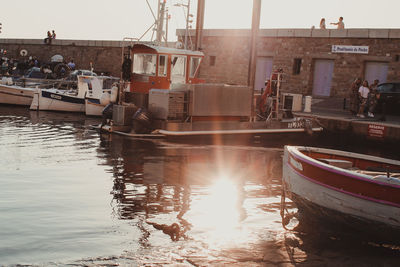 Fishing boats moored at harbor against sky