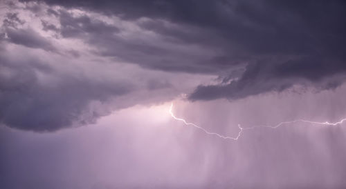 Low angle view of sunlight streaming through clouds