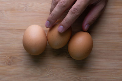 Close-up of hand holding eggs on table