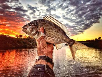 Reflection of man in lake against sky during sunset