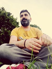 Portrait of young man sitting against plants