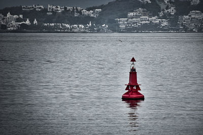 Red ship in sea against city