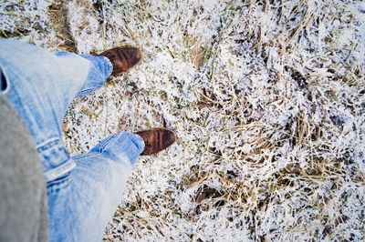 Low section of man standing on snow covered field