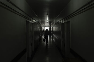 Rear view of man walking in illuminated building