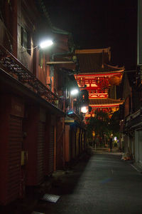 Illuminated street amidst buildings at night