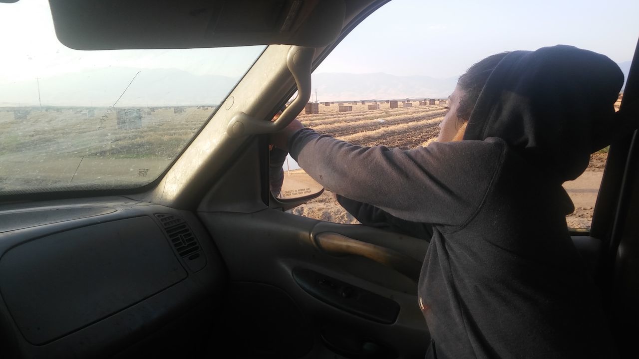 REAR VIEW OF WOMAN SITTING IN CAR WINDOW