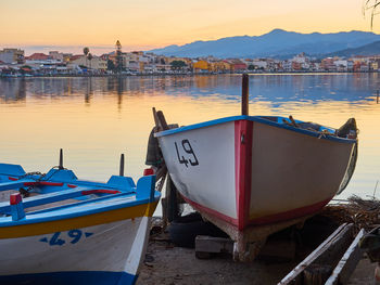 Boats moored at harbor against sky during sunset