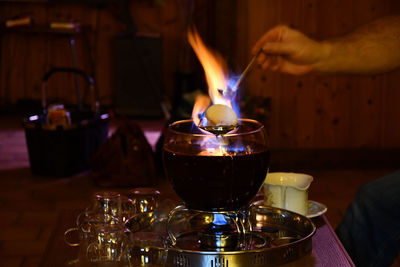 Waiter putting a burning sugarloaf over a bowl of feuerzangenbowle on a restaurant table