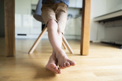 Boy with legs crossed at ankle sitting on chair