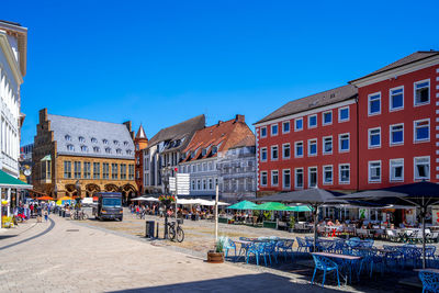 Buildings by street in city against clear blue sky