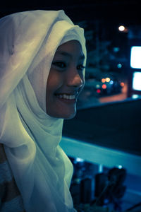 Happy woman wearing hijab in balcony at night