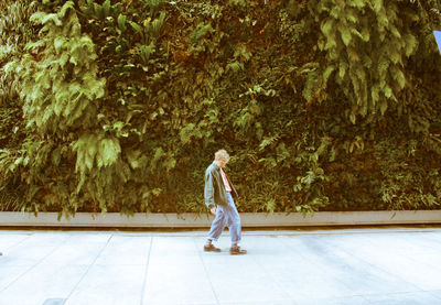 Side view of man walking on footpath against trees