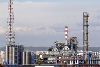 Communications tower in factory against sky