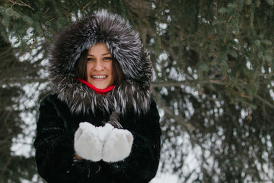 Portrait of smiling young woman standing in snow