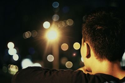 Rear view of man outdoors at night