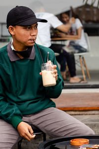 Man holding drink sitting on seat