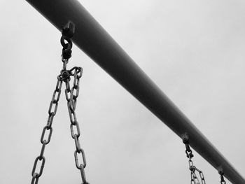 Low angle view of chain swing against sky