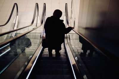 Rear view of man and woman standing on escalator