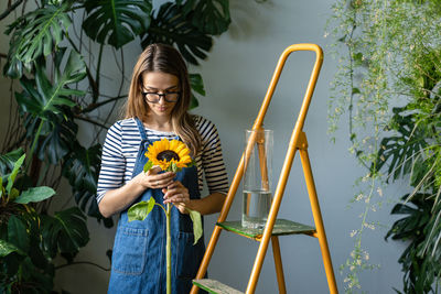 Smiling florist holding sunflower standing at flower shop