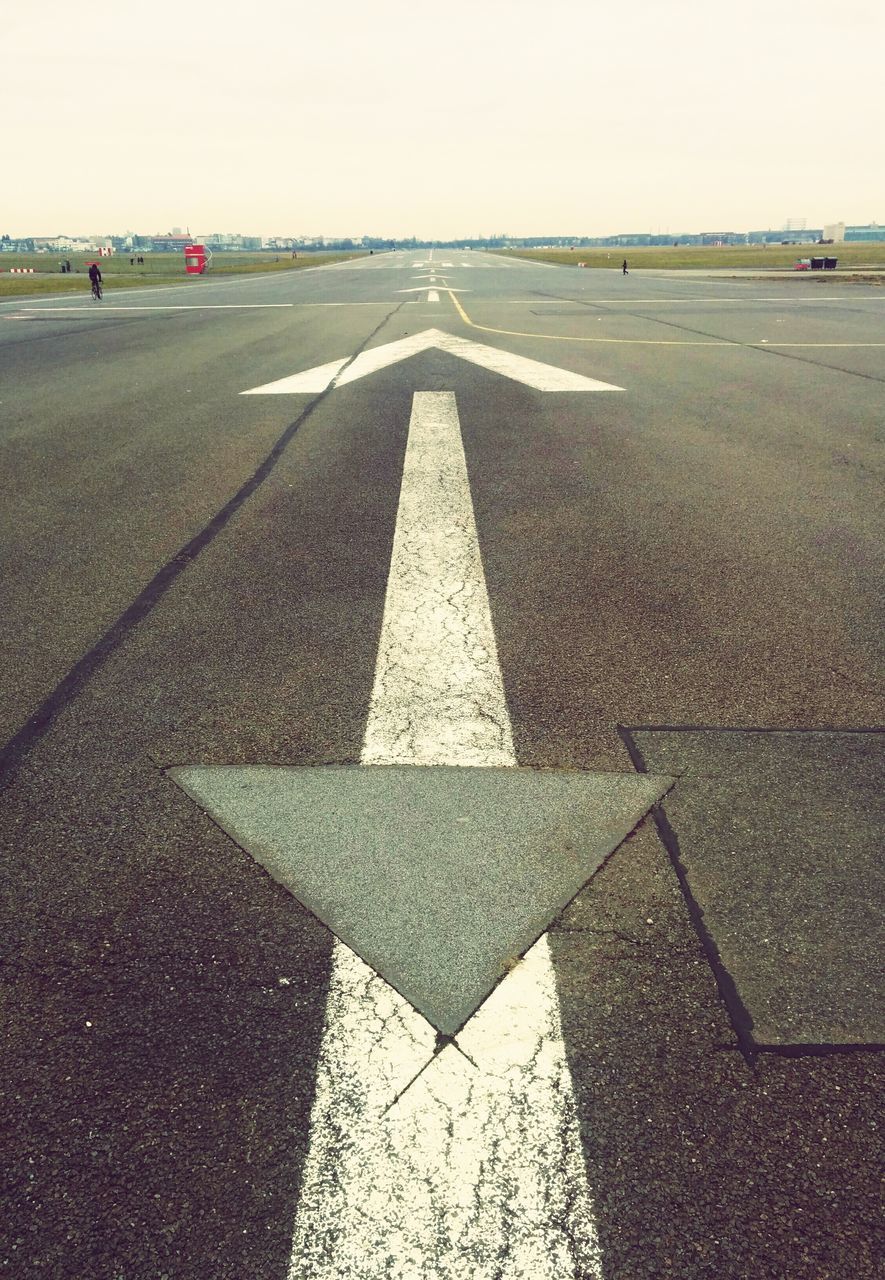 road marking, road, transportation, street, asphalt, the way forward, day, outdoors, sunlight, direction, high angle view, guidance, shadow, incidental people, travel, pattern, diminishing perspective, clear sky, arrow symbol, empty