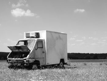 Abandoned vehicle on field against sky