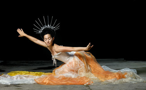 Young woman dancing against black background