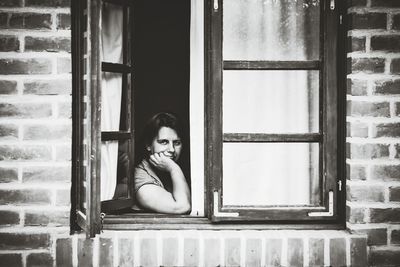 Portrait of woman looking through window