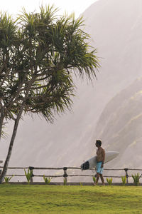 Young man walking and carrying surfboard