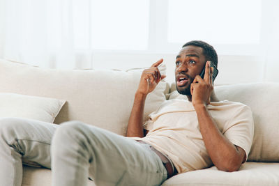 Young woman using phone while lying on bed at home