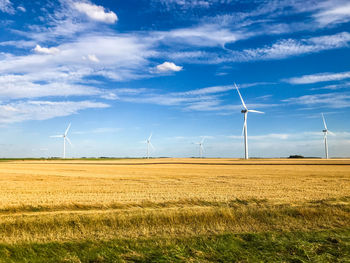 Wind turbines on field against sky